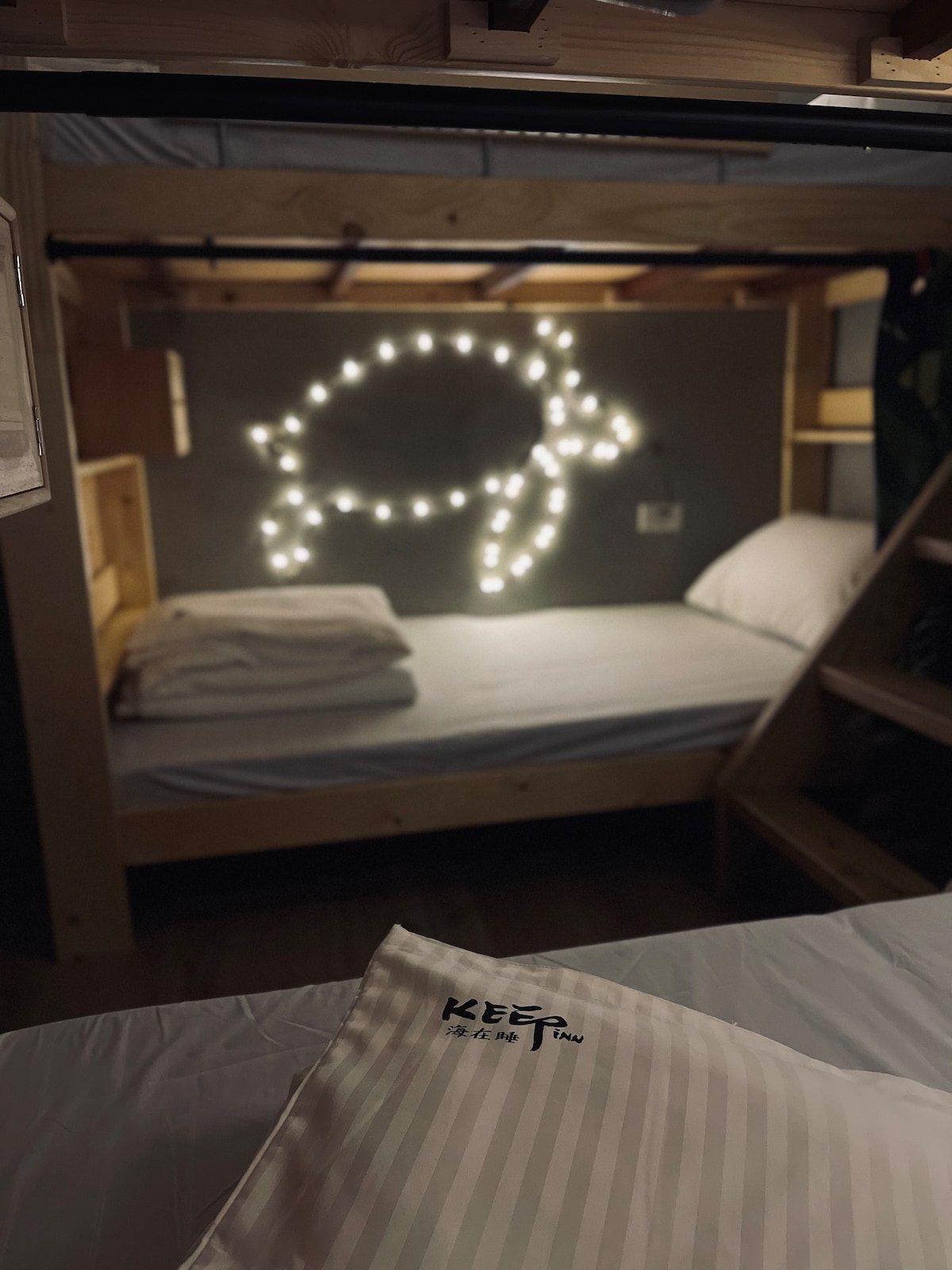 A cozy sleeping area is featured, with soft bedding arranged on a spacious bed. Ambient lights outline a turtle shape on the wall, creating a calming atmosphere. A striped pillow on the edge of the bed adds a touch of simplicity to the design.