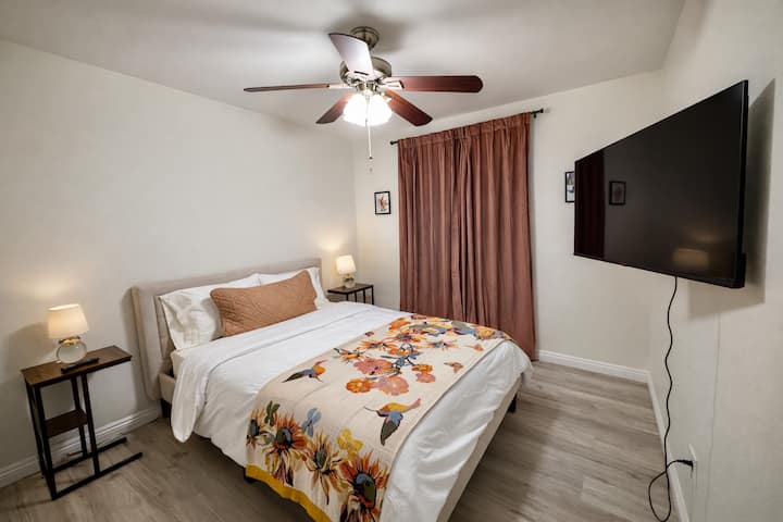 غرفة نوم مريحة تتميز بسرير بحجم كوين وتلفزيون وأجواء مريحة لقضاء ليالٍ مريحة.