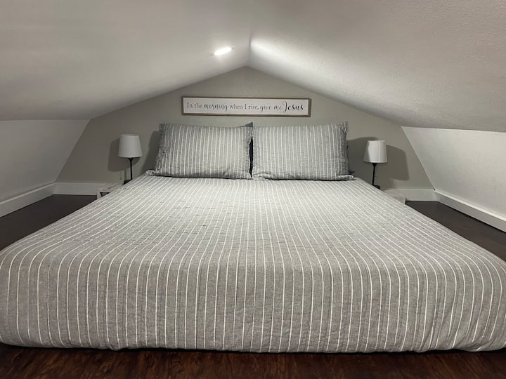 Loft abierto con cama tamaño queen y lámparas. Esta zona se puede ver desde la sala de estar y otro loft. 