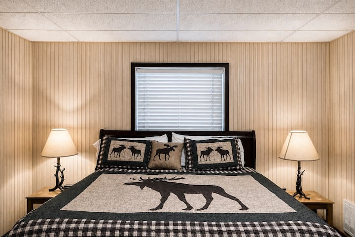 A comfortable room with a queen-size bed dressed in lodge-style bedding and accent pillows. 