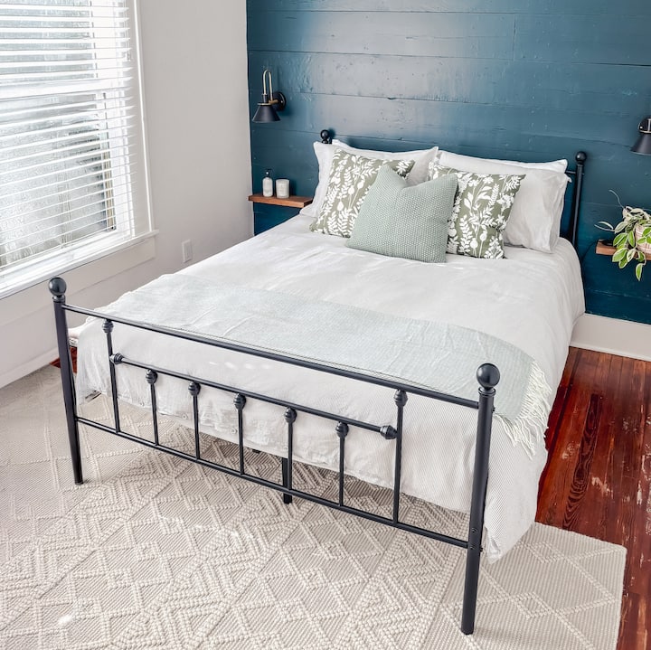 Oddýchnite si v tejto očarujúcej a príjemnej spálni s manželskou posteľou, kde sa štýl stretáva s pohodlím. Nápadná modrá dekoratívna stena dodáva pop pf osobnosť, ktorá sa dopĺňa očarujúcim kovovým rámom postele. Užite si to! 
