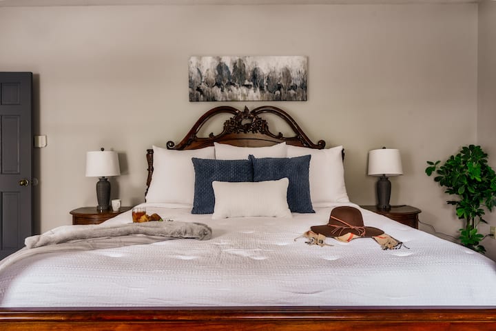 [Bedroom #1 Main Level] Features a king-sized bed, lamps with USB charger, an en-suite bathroom, a smart TV, a dresser, and a closet. 