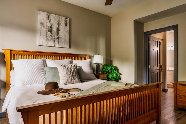 [Bedroom #3, Lower Level] Features a king-sized bed, en-suite bathroom, lamps with USB charger, a smart TV, a dresser, and a closet room