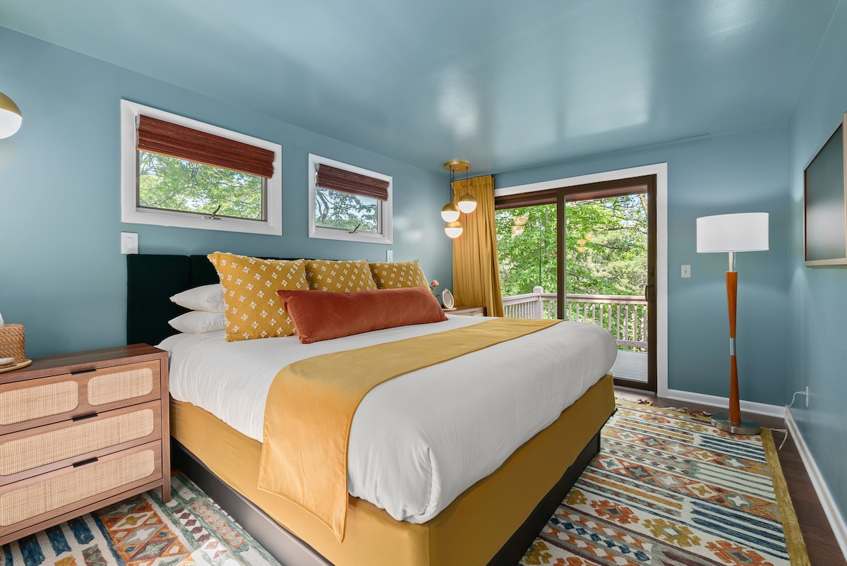 Chumba hiki cha kulala kina kitanda na televisheni.  Mlango unaoteleza huruhusu ufikiaji rahisi wa sitaha.