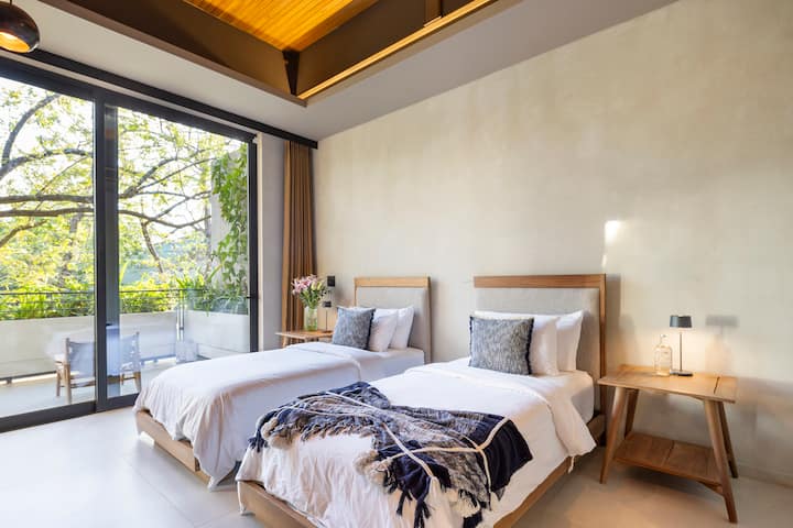 Spavaća soba u gornjem desnom kutu, s bračnim krevetom ili dva odvojena kreveta, stropnim ventilatorom, klima-uređajem, ormarom s vješalicama i sefom, ogledalom za cijelo tijelo, košarom za rublje