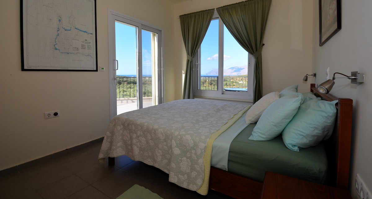 בית ההארחה Hawk's Nest, חדר שינה ראשי, עם מיטת קווין סייז ומרפסת גדולה המקיפה את מפרץ קיסאמוס והים האגאי, ומרפסת גג פרטית עם נוף מרהיב לים ולהרים.