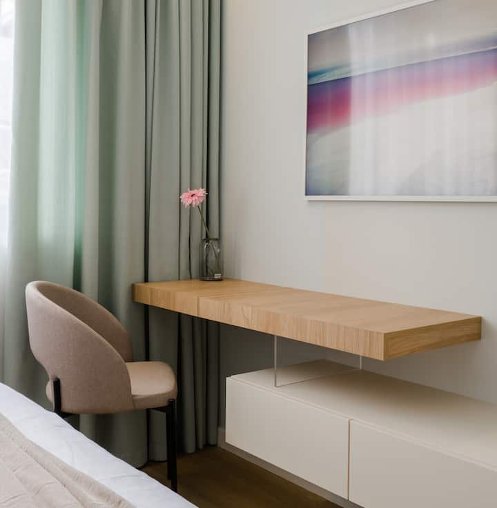 פינה אלגנטית עם כיסא קטיפה, שולחן עץ צף ווילונות רכים - מושלם לקריאה, עבודה או להתכונן בשלווה.