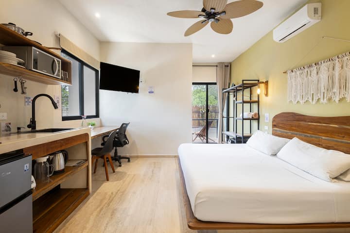 Cama tamaño king con armario abierto justo al lado, con toallas de piscina, toallas de baño, perchas, plancha y una caja fuerte para computadoras portátiles. También puedes ver la puerta corrediza que conduce al balcón privado.