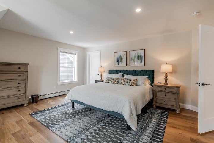 غرفة نوم كبيرة الحجم في الطابق الثاني مع سرير كينج ومنطقة جلوس وخزانة ملابس.