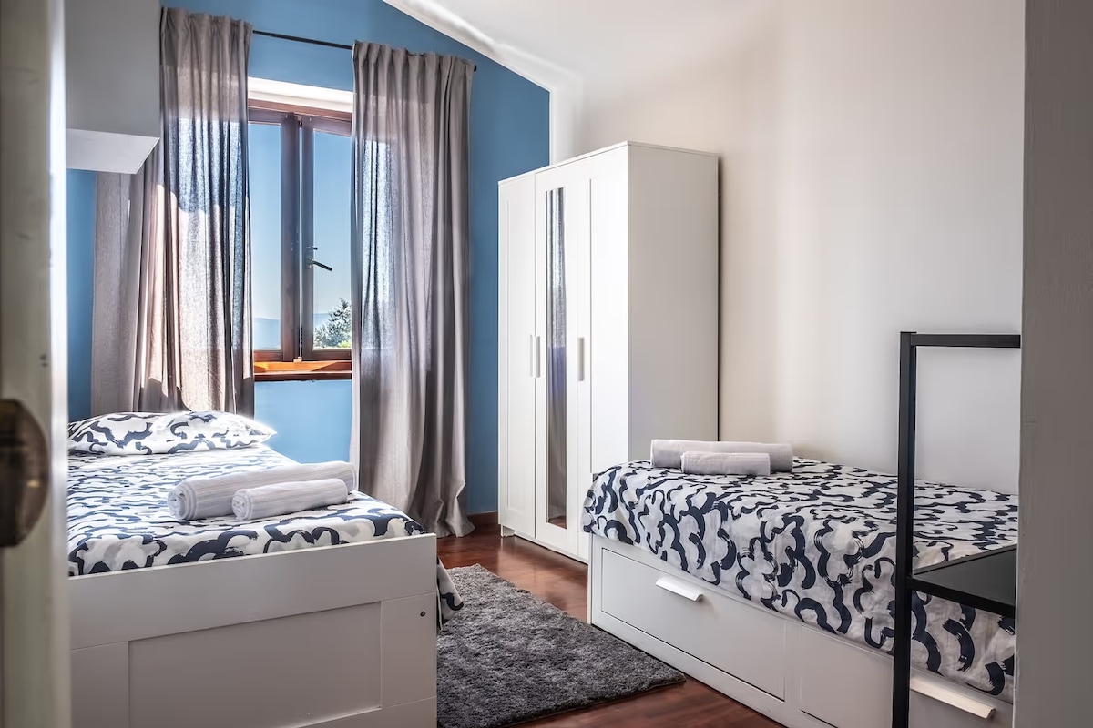 Chumba cha Bluu: Chumba kinachoweza kubadilika chenye vitanda viwili vya mtu mmoja, kimojawapo kinaweza kuunganishwa ili kuunda kitanda cha watu wawili.