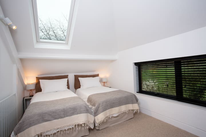 ห้องนอนชั้นบนมีเตียงเดี่ยวสองเตียง สว่างด้วยหน้าต่าง 4 บาน