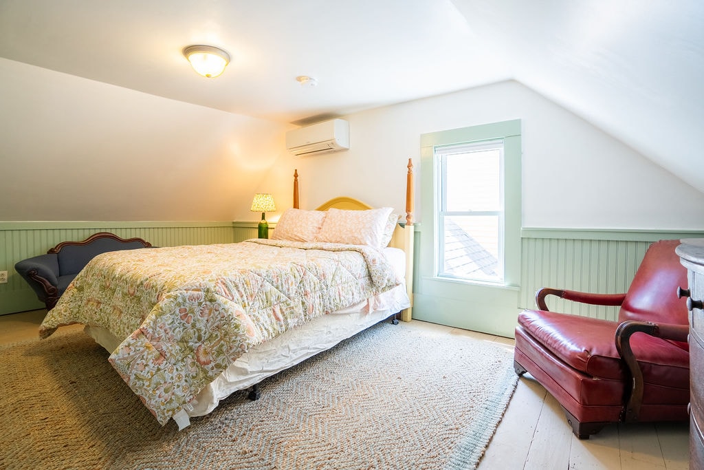 Upstairs in the Cape, a bedroom has a queen bed, a dresser, closet, and seating. A heat pump provides air conditioning and heat to keep you comfortable.