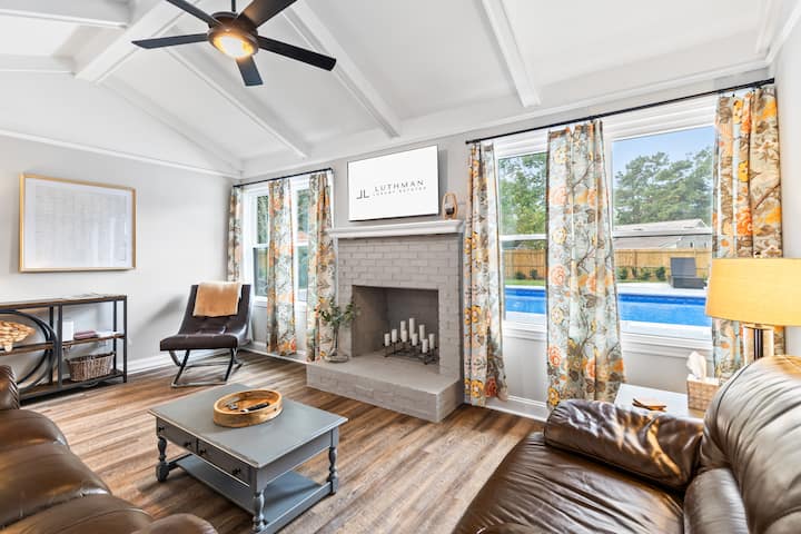 Ontspan in de lichte woonkamer met uitzicht op het zwembad, waar comfortabele zitplaatsen en natuurlijk licht een perfecte ruimte creëren voor familietijd of rustige momenten tussen avonturen in Charleston.