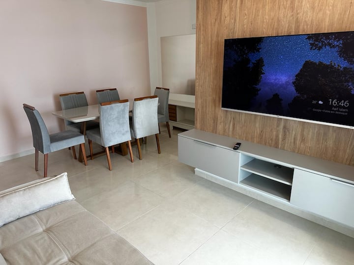 ห้องนั่งเล่นทันสมัยและอบอุ่นพร้อมทีวีขนาดใหญ่ โซฟาที่สะดวกสบาย และแสงธรรมชาติ