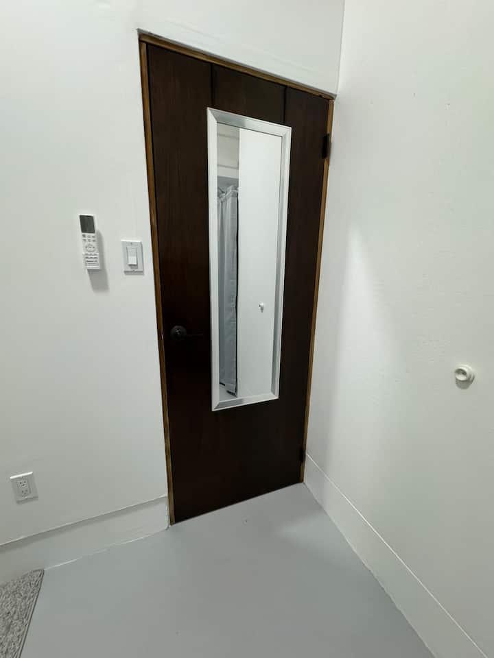 Inside the bedroom, there is a full-length mirror over the door. 
