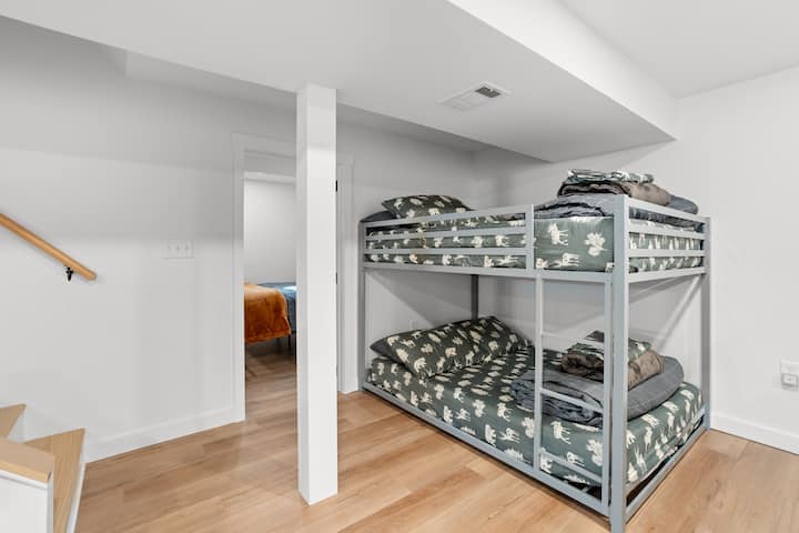 Chumba cha kulala cha ghorofa ya chini ikiwa ni pamoja na kitanda cha ghorofa (vitanda 2 kamili), meza ya sehemu, meza ya urefu wa kaunta na viti na televisheni mahiri.

Kumbuka: Chumba hiki cha kulala ni sehemu ya pamoja na Sebule 2.