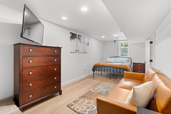 Chumba cha kulala cha ghorofa ya chini ikiwa ni pamoja na kitanda cha malkia, kifurushi n’ play, futoni, kabati, kabati la kujipambia na televisheni mahiri.