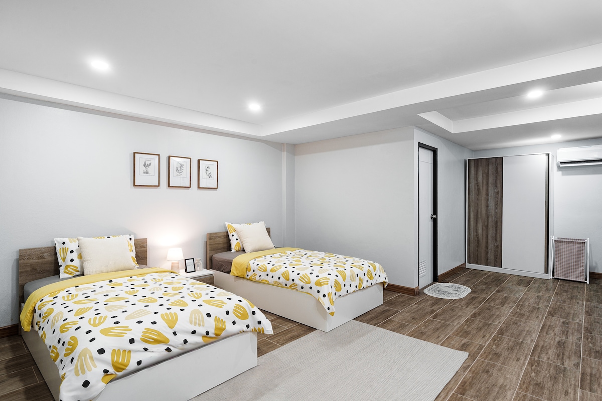 غرفة نوم مشرقة وعصرية مع سريرين مفردين ومساحة تخزين واسعة وتلفزيون وتكييف هواء.