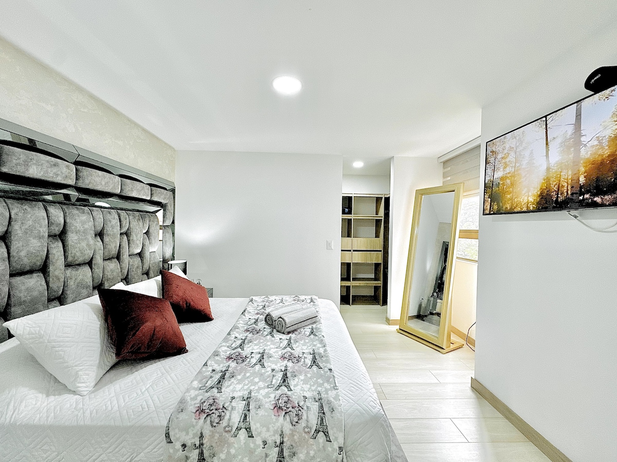 Elegantna soba s bračnim krevetom, tapeciranim uzglavljem i televizorom na zidu. Uključuje ogledalo u punoj veličini i otvoreni ormar, stvarajući udoban, svijetao prostor koji je savršen za odmor.