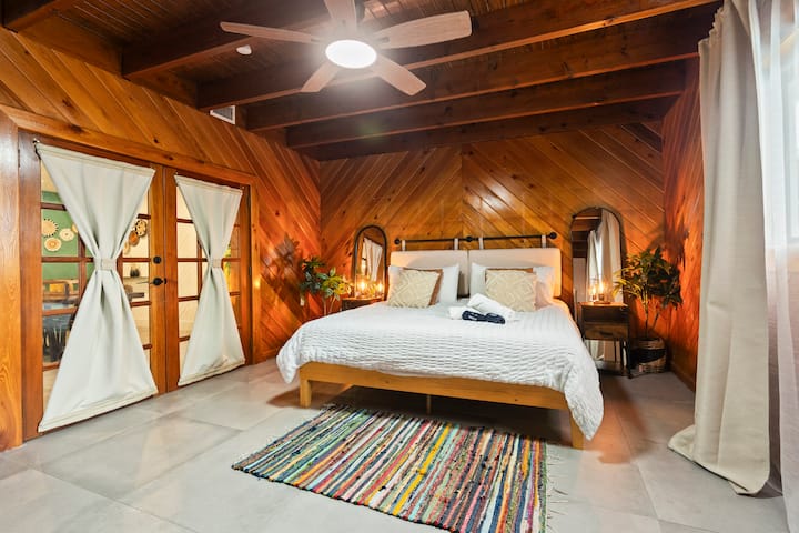 Esta acogedora habitación cuenta con un aspecto cálido y natural con sus ricas paredes con paneles de madera, creando un ambiente acogedor y rústico. Su proximidad a la piscina mejora el ambiente general, que combina a la perfección la vida interior y exterior. 