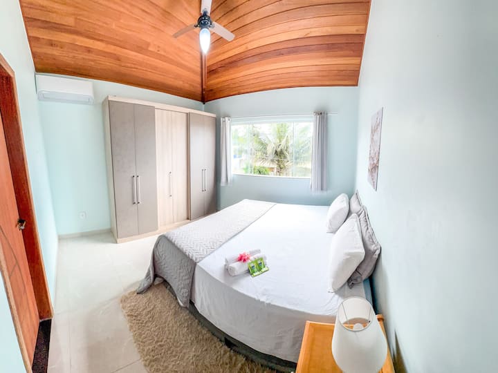 Amplio dormitorio con aire acondicionado, ventilador de techo y alfombra.