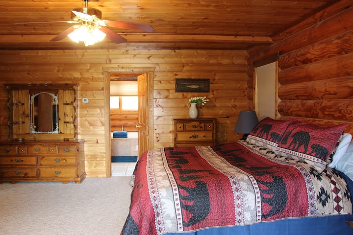 Lodges Main Level Master Bedroom with attached private bathroom. Kingsize-dobbeltseng, loftsventilator, tv kommode, udsigt over søen fra din balkon.