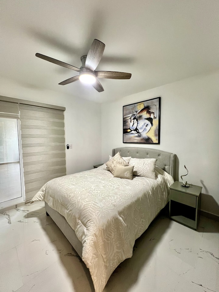Camera da letto principale con letto matrimoniale, dotata di piumini, cuscini e cuscini decorativi, che creano un'atmosfera accogliente ed elegante per il tuo riposo.