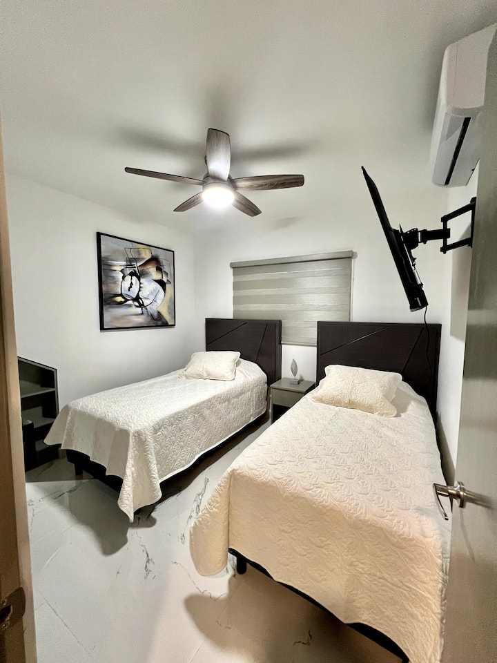 Una camera da letto secondaria con due letti singoli, dotata di piumoni, cuscini e cuscini decorativi, che creano un'atmosfera accogliente ed elegante per riposare.