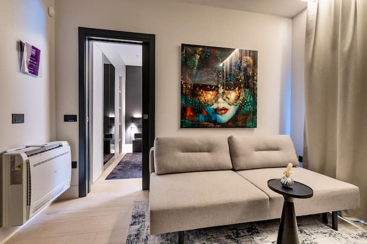 טרקלין עכשווי הכולל ספה נפתחת אלגנטית, אמנות מודרנית תוססת ותאורה אווירית רכה. מקום מפלט מסוגנן כדי להירגע או ליהנות מערב שקט בפנים.