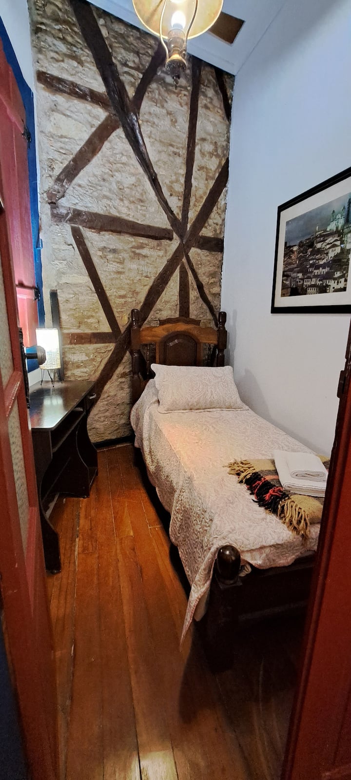 Საძინებელი ერთადგილიანი საწოლით, ლამპით, სარკითა და თაროებით.