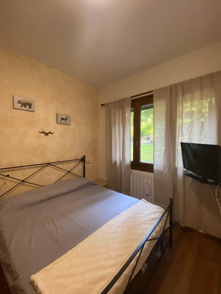 Habitación doble con TV, armario de 5 puertas, ventana con vistas al jardín del condominio