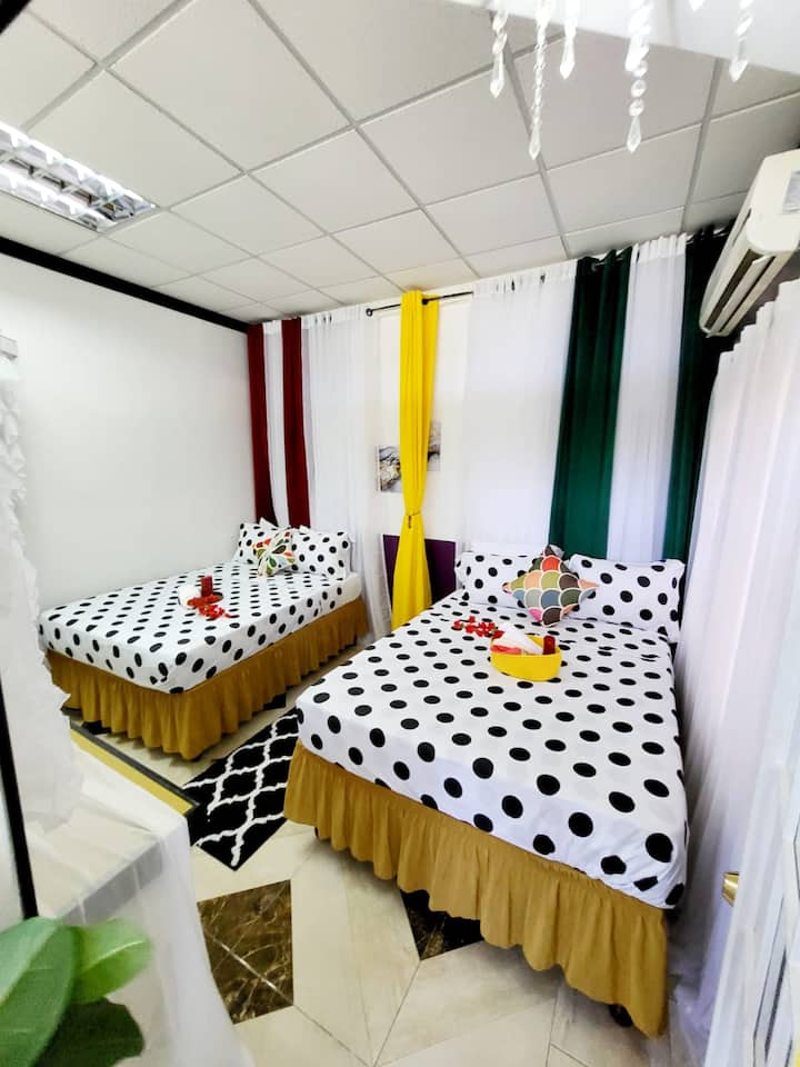 Tento štýlový priestor ponúka dve pohodlné postele zdobené hravou posteľnou bielizňou s polkou, ktorá je doplnená výbuchom farebnej výzdoby. Vychutnajte si živú kombináciu červených, zelených, žltých a bielych závesov, ktoré vytvárajú veselú atmosféru ideálnu na oddych.