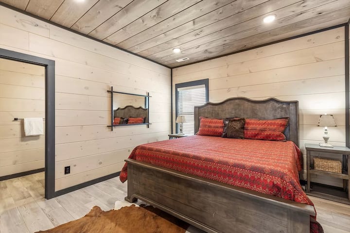Bedroom 4 on the upper level offers a king bed, a large TV, a private bathroom, and a shower. The highlight of this room is the amazing sunset view over the treeline, providing the perfect backdrop for your evening relaxation.