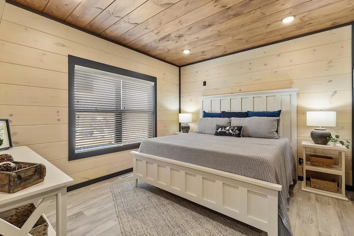Bedroom 2, also on the main level, features a king-size bed, a large TV, a private restroom with a shower, and a closet. Conveniently located near the main entrance, this room offers easy access to the rest of the house.