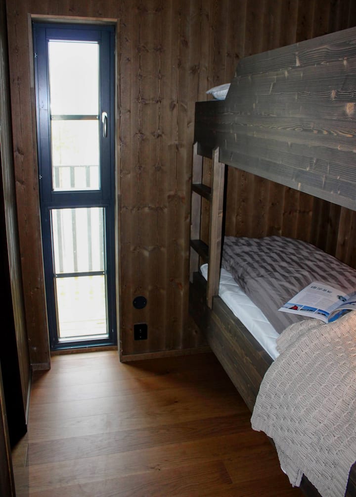 Litera hecha a medida en madera con cuentas con un toque rústico y luz natural de una ventana estrecha.