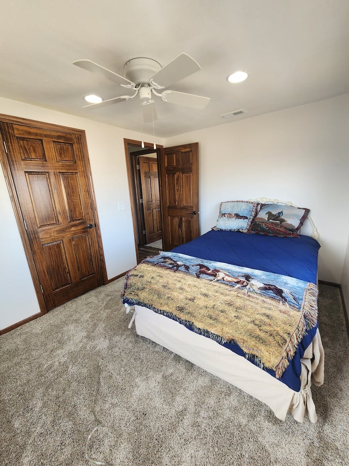 سرير كامل الحجم ذو طابع غربي في غرفة نوم مع خزانة ونافذتين. 
هناك طاولة صغيرة مع مصباح أيضًا!