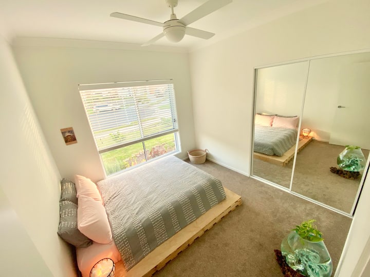 Брачен кревет (широк 150-179 см) на ниска основа на палети со вентилатор и огледален плакар.