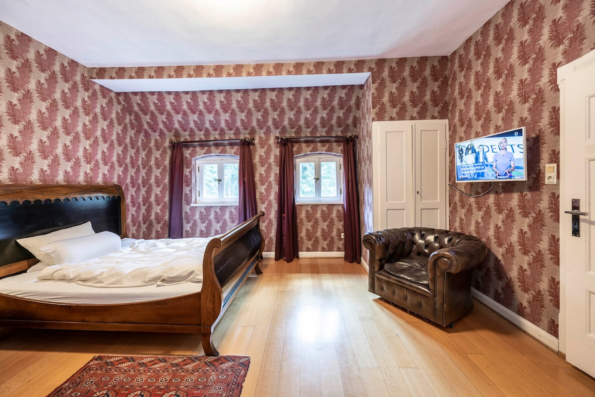 Parkiralište: Povijesni štih se osjeća u parkiralištu. Drveni bračni krevet s zakrivljenim elementima i širokim pogledom na travnjake u park.
Svijetla kupaonica u sklopu apartmana s tušem, kadom, kadom i WC-om.