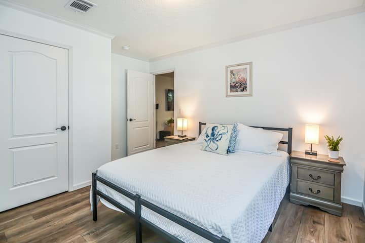 Kitanda cha malkia chenye starehe kilicho na stendi za usiku zilizo na droo mbili. 