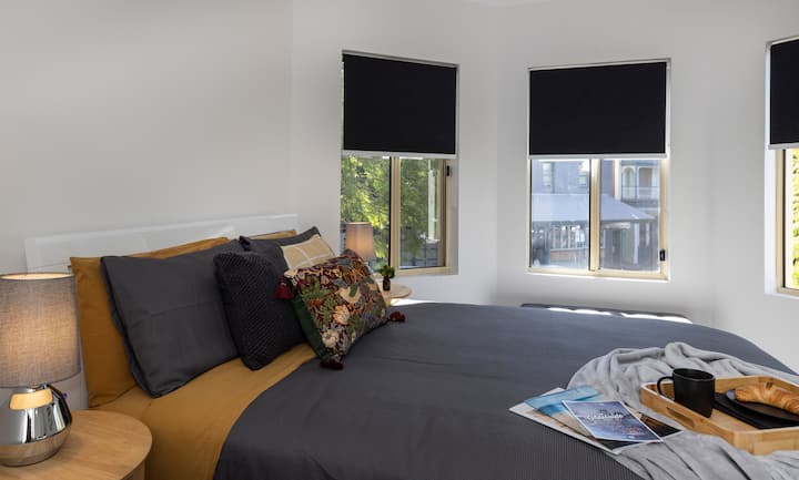 Slaapkamer 1 met queensize bed, royale ingebouwde badjas en een luxe fluwelen draaistoel om te ontspannen en te genieten van het lommerrijke uitzicht. Carrington St ligt centraal en dicht bij alles, maar is ook een rustig rustig  toevluchtsoord.