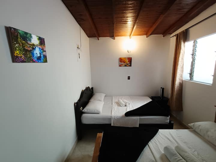 quarto com duas camas de casal, ventiladores e roupas de guarda