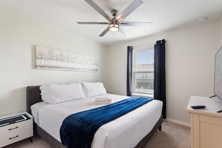 Elegantná hlavná izba na druhom poschodí s luxusnou posteľou King, vlastnou kúpeľňou, inteligentným televízorom, stropným ventilátorom a zatemňovacími závesmi pre pokojný spánok.