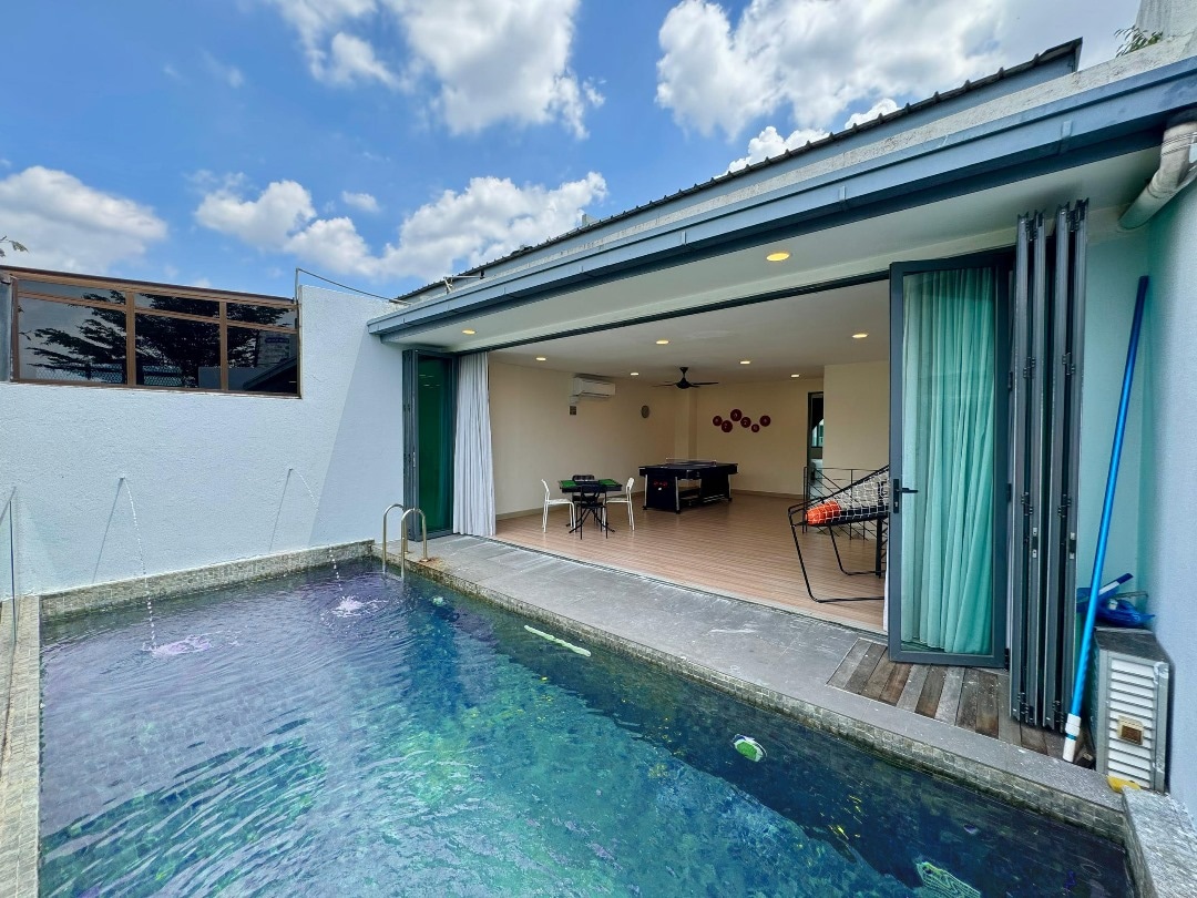 A private pool is visible at the forefront, framed by a serene deck. The open space connects to an indoor area featuring game tables and comfortable seating. Large glass doors enhance the inviting atmosphere, allowing natural light to fill the space while revealing expansive blue skies beyond.