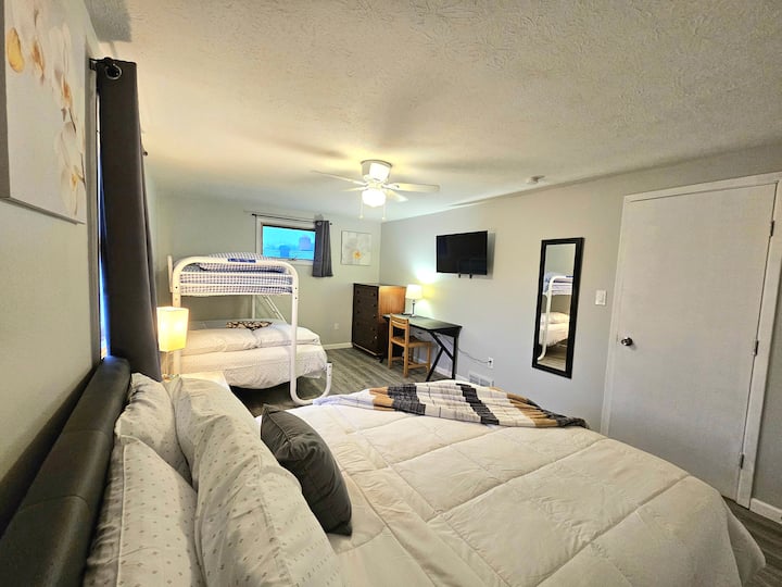 Dormitorio grande en la planta superior con cama tamaño queen, cama doble y cama doble (litera), rincón de oficina y TV inteligente