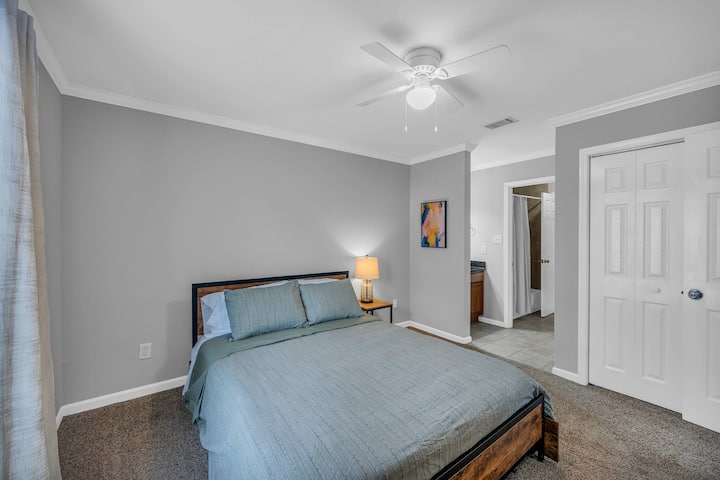 Manželská posteľ s úložnými zásuvkami, pripojeným súkromným umývadlom s umývadlom a šatníkom.