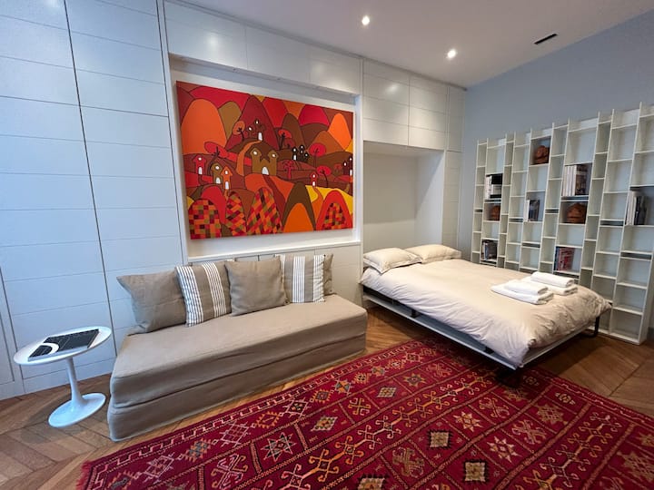 Спална соба со двоен кревет и два единечни душека на подот со телевизор.