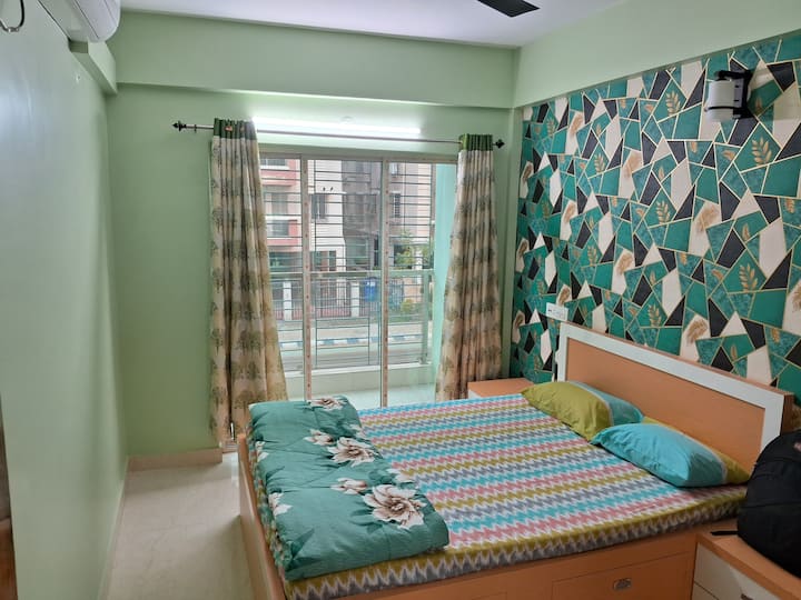 Добре оборудваната климатизирана спалня с балкон включва основни мебели като легло, гардероб, климатик, осветление заедно с удобно спално бельо и декор, за да се създаде релаксиращо пространство.