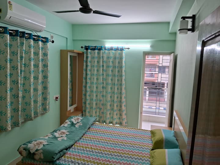 Добре оборудваната климатизирана спалня с балкон включва основни мебели като легло, гардероб, климатик, вентилатор, осветление заедно с удобно спално бельо и декор, за да се създаде релаксиращо пространство. В тази стая има и баня.