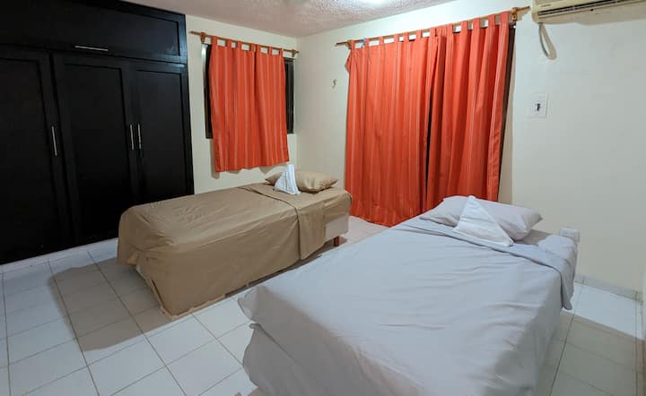 חדר עם שתי מיטות זוגיות. דלת חלון עם מרפסת המשקיפה על אזור הבריכה והאוקיינוס.