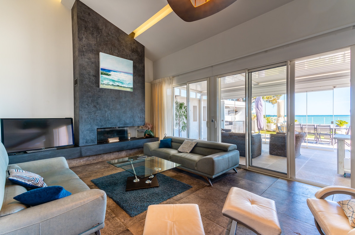 A spacious living area is featured, equipped with a modern sofa and a sleek coffee table on a textured rug. Large glass doors offer an unobstructed view of the outdoor terrace and surrounding scenery, allowing natural light to brighten the room.